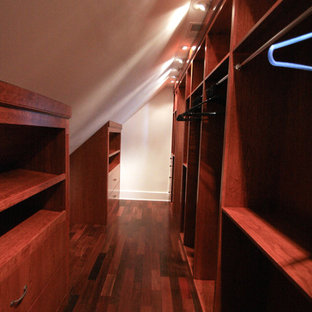 Immagine di una grande cabina armadio unisex classica con ante in legno scuro e pavimento in legno massello medio