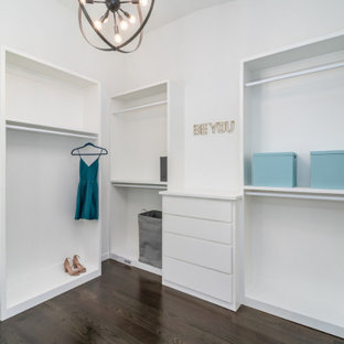 Diseño de armario y vestidor de mujer, moderno, grande, con armarios abiertos, puertas de armario blancas, suelo marrón y suelo de madera en tonos medios