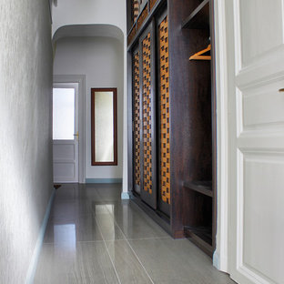 Ejemplo de armario vestidor unisex, actual, de tamaño medio, con puertas de armario de madera oscura y suelo de baldosas de cerámica
