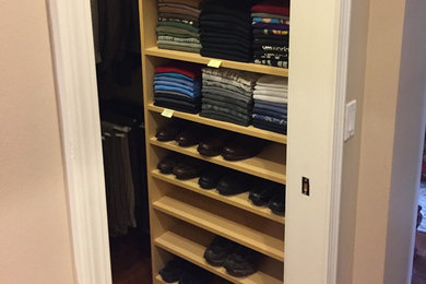 Example of a small classic men's dark wood floor and brown floor walk-in closet design in Los Angeles with open cabinets and light wood cabinets