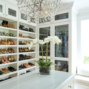 Example of a country walk-in closet design in Boston with glass-front cabinets and white cabinets