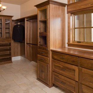 Immagine di una grande cabina armadio unisex mediterranea con ante con riquadro incassato, ante in legno bruno e pavimento in travertino