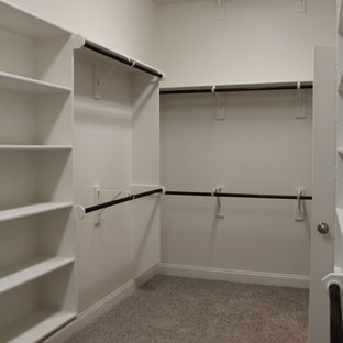 Imagen de armario vestidor grande con armarios abiertos, puertas de armario blancas, moqueta y suelo gris