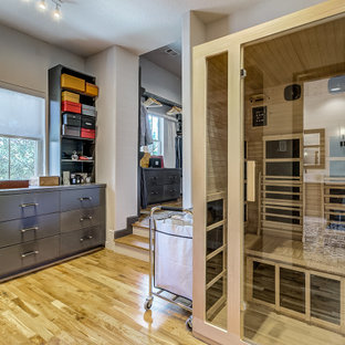 Immagine di un'ampia cabina armadio unisex mediterranea con ante lisce, ante grigie, parquet chiaro e pavimento marrone