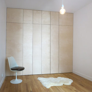 Cette photo montre un grand dressing room moderne neutre avec des portes de placard en bois clair et un sol en bois brun.
