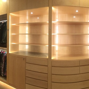 Inredning av ett modernt mycket stort walk-in-closet för könsneutrala, med släta luckor, skåp i ljust trä och ljust trägolv
