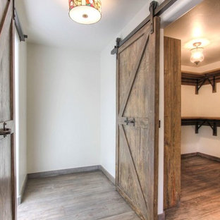 Ejemplo de armario vestidor unisex, de estilo de casa de campo, grande, con armarios abiertos, puertas de armario de madera oscura y suelo de madera en tonos medios