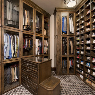 Foto di un grande spazio per vestirsi per uomo chic con ante di vetro, ante in legno bruno e pavimento multicolore