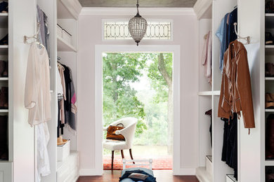 Inspiration pour un dressing room pour une femme avec des portes de placard blanches, parquet foncé et un sol marron.