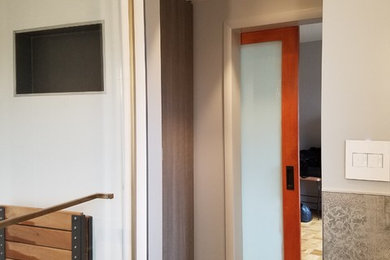 Example of a small trendy men's porcelain tile and gray floor dressing room design in New York with flat-panel cabinets and medium tone wood cabinets