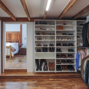 Ejemplo de armario vestidor unisex, de estilo de casa de campo, grande, con armarios abiertos, puertas de armario blancas, suelo de madera en tonos medios y suelo marrón