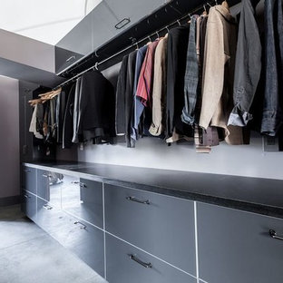 Foto de armario vestidor de hombre, minimalista, grande, con armarios con paneles lisos, puertas de armario grises, suelo de cemento y suelo gris