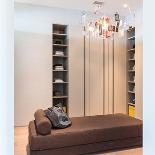 Idee per un grande spazio per vestirsi unisex minimalista con nessun'anta, ante in legno chiaro e pavimento in bambù