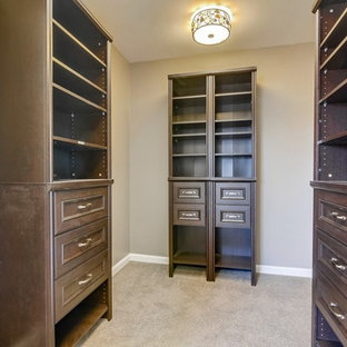 Modelo de vestidor unisex, tradicional renovado, grande, con armarios con paneles con relieve, puertas de armario de madera en tonos medios, moqueta y suelo gris