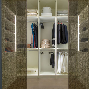 Ejemplo de armario vestidor unisex, bohemio, grande, con armarios tipo vitrina, puertas de armario blancas, suelo de madera en tonos medios y suelo beige