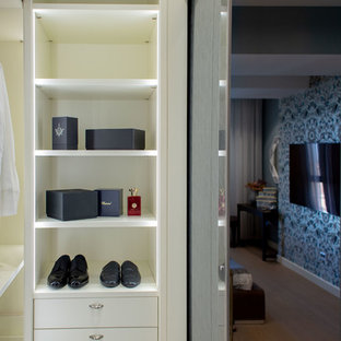 Imagen de armario vestidor unisex, bohemio, grande, con armarios tipo vitrina, puertas de armario blancas, suelo de madera en tonos medios y suelo beige