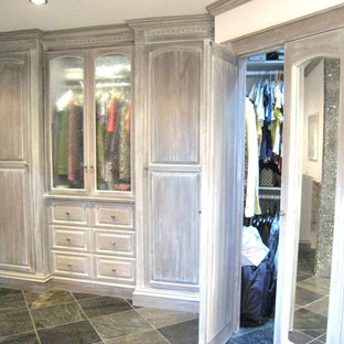 Idee per una grande cabina armadio unisex classica con ante con bugna sagomata, ante con finitura invecchiata e pavimento in ardesia