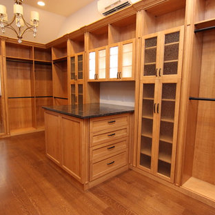 Esempio di una grande cabina armadio chic con ante di vetro e ante in legno scuro