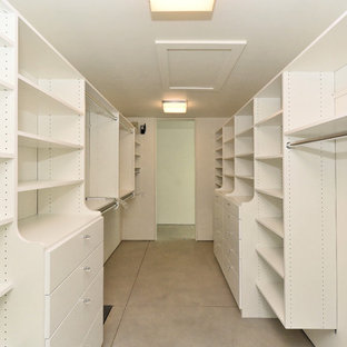 Foto de armario vestidor unisex, moderno, de tamaño medio, con armarios con paneles lisos, puertas de armario blancas, suelo de cemento y suelo gris
