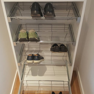 Imagen de armario unisex, moderno, pequeño, con armarios con paneles lisos, puertas de armario blancas, suelo laminado y suelo marrón
