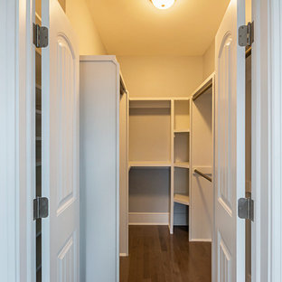 Ispirazione per una cabina armadio unisex stile americano di medie dimensioni con ante bianche, pavimento in laminato, pavimento marrone e nessun'anta