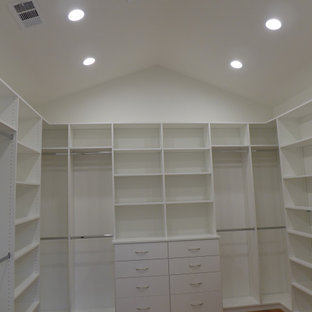 Diseño de armario vestidor unisex y abovedado, de estilo de casa de campo, extra grande, con armarios con paneles lisos, puertas de armario blancas, suelo de madera clara y suelo marrón