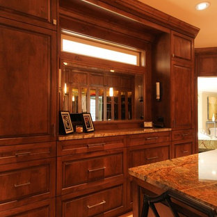 Diseño de armario vestidor unisex, ecléctico, extra grande, con armarios con paneles con relieve, puertas de armario de madera oscura y suelo de madera clara