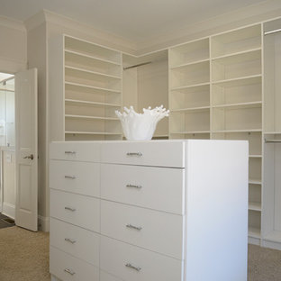 Diseño de armario vestidor de estilo de casa de campo, grande, con puertas de armario blancas y moqueta