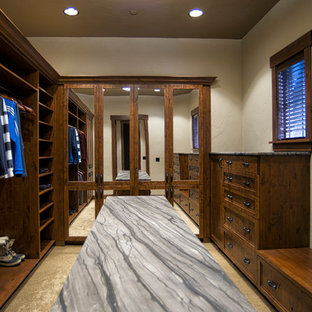 Foto di una cabina armadio unisex rustica con ante con riquadro incassato, ante in legno bruno, moquette e pavimento beige
