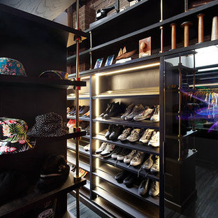 Immagine di un'ampia cabina armadio unisex boho chic con ante nere e pavimento in legno massello medio