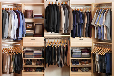 Diseño de armario vestidor de hombre tradicional de tamaño medio con armarios abiertos, puertas de armario de madera clara, suelo de madera oscura y suelo marrón