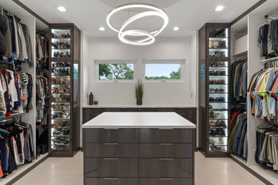 Example of a mid-sized trendy gender-neutral light wood floor and beige floor walk-in closet design in Tampa with flat-panel cabinets and dark wood cabinets