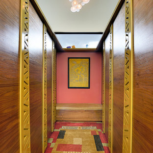 Immagine di una cabina armadio unisex eclettica di medie dimensioni con ante lisce, ante in legno scuro, moquette e pavimento multicolore