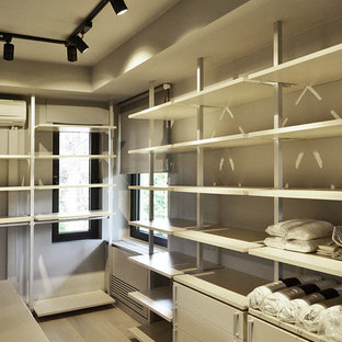 Imagen de armario vestidor actual con armarios abiertos, puertas de armario beige y suelo de madera clara