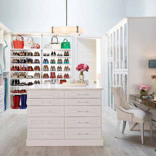Elegant gender-neutral light wood floor walk-in closet photo in Other with white cabinets and raised-panel cabinets