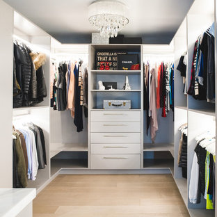 Diseño de vestidor unisex, contemporáneo, grande, con armarios abiertos, puertas de armario blancas, suelo de madera clara y suelo marrón