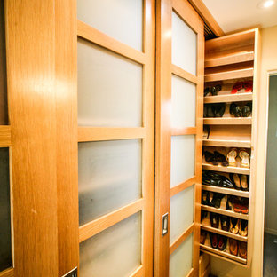 Immagine di una cabina armadio unisex tradizionale di medie dimensioni con ante di vetro, ante in legno scuro, pavimento in cemento e pavimento marrone