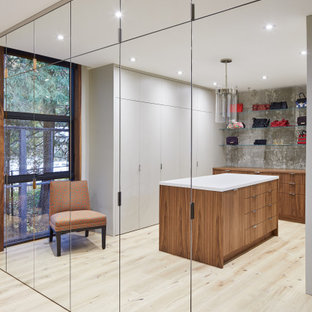 Immagine di un'ampia cabina armadio unisex design con ante lisce, ante in legno scuro, pavimento in compensato e pavimento beige