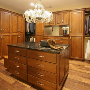 Imagen de armario vestidor unisex, bohemio, grande, con suelo de madera en tonos medios, armarios con paneles con relieve, puertas de armario de madera oscura y suelo marrón