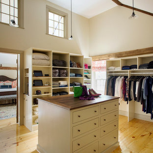 Ejemplo de vestidor unisex, de estilo de casa de campo, grande, con armarios abiertos, puertas de armario beige y suelo de madera clara