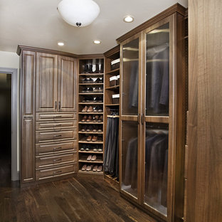 Idee per una cabina armadio unisex chic di medie dimensioni con ante con bugna sagomata, ante in legno scuro e parquet scuro