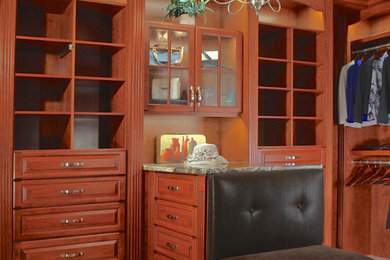 Large classic walk-in wardrobe in Chicago with raised-panel cabinets, medium wood cabinets and travertine flooring.