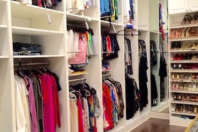 Huge elegant women's dark wood floor walk-in closet photo in New Orleans with open cabinets and white cabinets