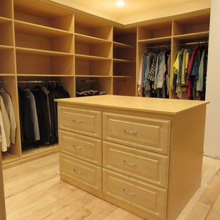 Immagine di una grande cabina armadio unisex chic con ante con bugna sagomata, ante in legno chiaro, parquet chiaro e pavimento marrone