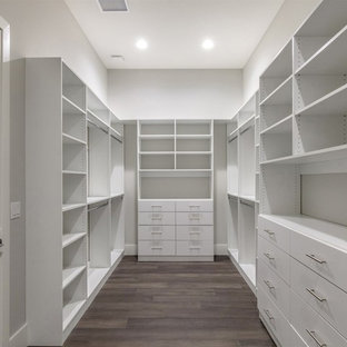 Exemple d'un grand dressing chic neutre avec un placard à porte plane, des portes de placard blanches, un sol en bois foncé et un sol marron.