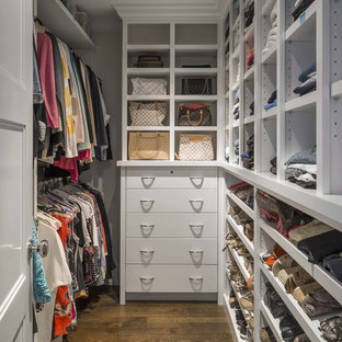 Modelo de armario vestidor de mujer, clásico renovado, de tamaño medio, con armarios con paneles lisos, puertas de armario blancas y suelo de madera en tonos medios