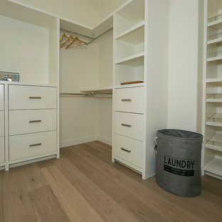 Idee per una grande cabina armadio unisex design con ante lisce, ante bianche e parquet chiaro