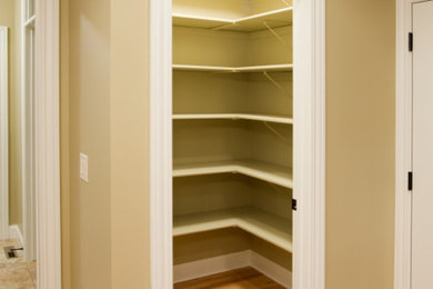Diseño de armario vestidor unisex clásico pequeño con armarios abiertos, puertas de armario blancas, suelo de madera clara y suelo beige