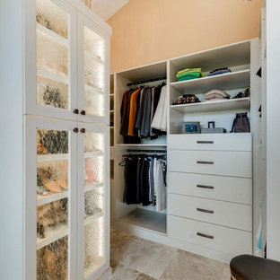 Modelo de armario y vestidor mediterráneo, grande, con armarios tipo vitrina, puertas de armario beige, suelo de travertino y suelo beige
