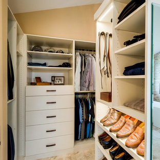 Ejemplo de armario y vestidor mediterráneo, grande, con armarios tipo vitrina, puertas de armario beige, suelo de travertino y suelo beige